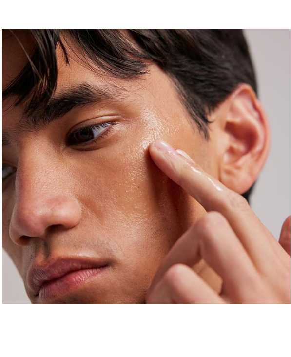 Close-up of a person applying skincare product to their face.